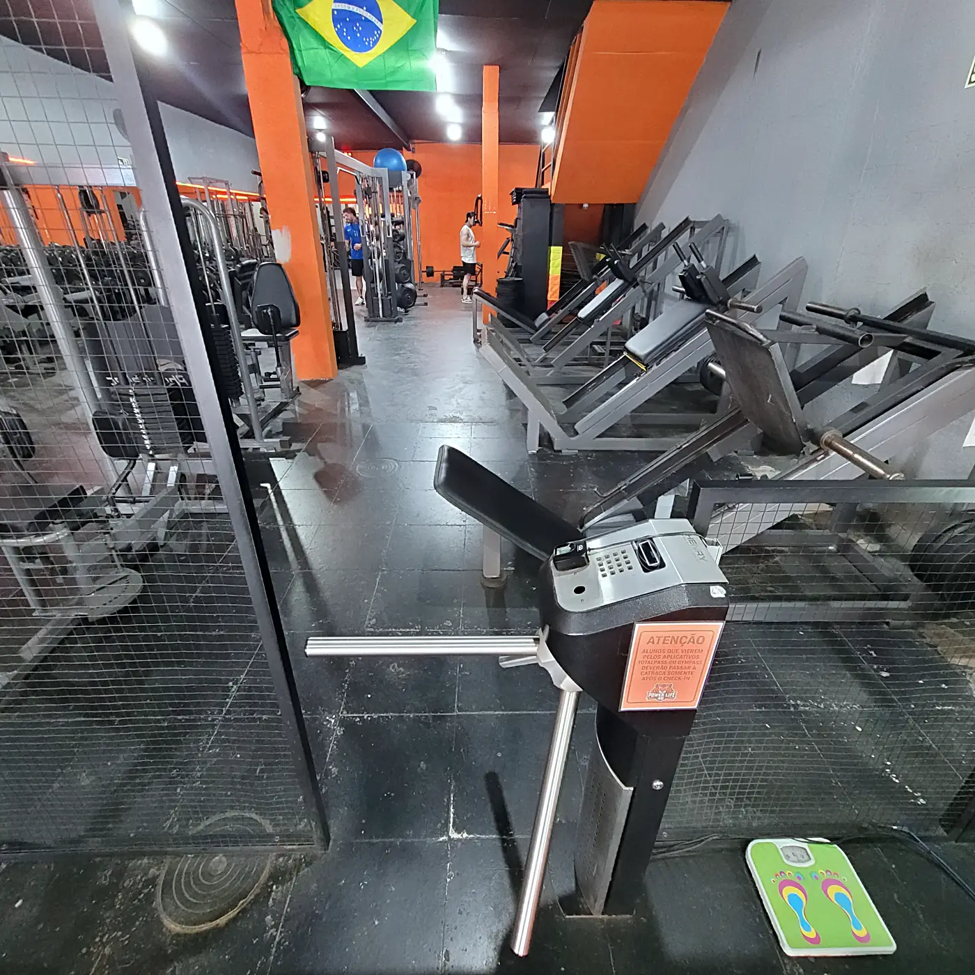 Catraca de acesso da PowerLife 4D com o salão de musculação ao fundo